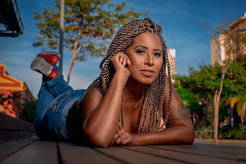Smiling woman with braids lying outdoors in Rio de Janeiro, sunny day.